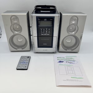 May include: A silver Curtis stereo system with two speakers, a remote control, and an instruction manual. The stereo has a CD player and a digital display. The instruction manual is labeled "Dining Room".