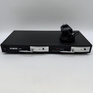 May include: A black RSQ Pro UHF dual channel wireless receiver with silver aerials and control panels. The receiver has a power adapter with a black cable. The text "RSQ Pro" and "UHF" are visible on the device.