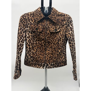 May include: A brown and tan leopard print jacket with a zipper closure, two front pockets, and a collared neckline. The jacket is displayed on a hanger against a white background.