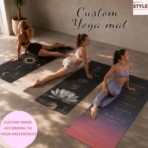 May include: Three rectangular yoga mats featuring distinct designs: one with a celestial sun and moon pattern, one with a white lotus flower, and one with a gradient sunset background and text including Breathe, Focus, Strength, and Balance.