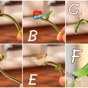 May include: A collection of miniature glass figurines, each depicting a different insect or animal perched on a curved glass stem with a leaf. The figurines include a ladybug, butterfly, snail, bee, bird, and a seal.