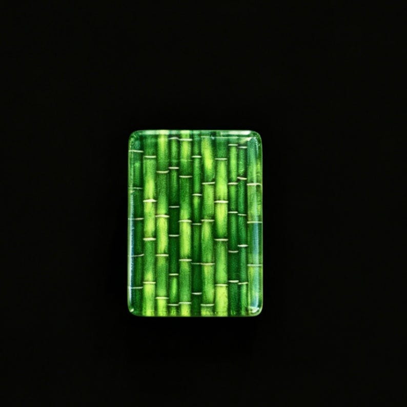 May include: A rectangular glass tile featuring a vibrant green bamboo stalk pattern. The design displays multiple vertical stalks in varying shades of lime and forest green, with horizontal nodes and a smooth, glossy finish on the surface.