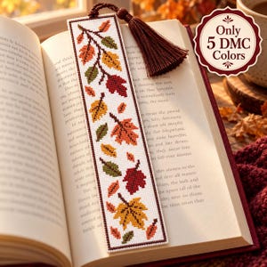 May include: A rectangular cross-stitch bookmark featuring a pattern of autumn leaves in shades of red, orange, yellow, and green on a white background. The bookmark is topped with a dark brown tassel and includes text stating Only 5 DMC Colors.