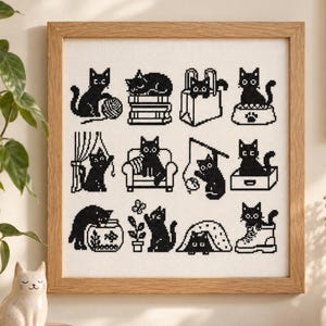 May include: A square cross-stitch embroidery in a light wood frame featuring a grid of twelve black cat illustrations on white fabric. The cats are depicted in various activities including playing with yarn, sitting in a box, and hiding in a boot.