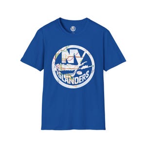 May include: A royal blue short-sleeve t-shirt featuring a circular graphic on the chest. The graphic contains the text NY ISLANDERS in white, overlaid on a colorful map design with a white circular border and a hockey stick silhouette.