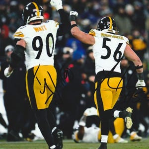 May include: A photograph of two football players wearing white jerseys with black and yellow accents, featuring the numbers 90 and 56 on the back. The players are celebrating with arms raised, and the image includes two black ink signatures on the jerseys.