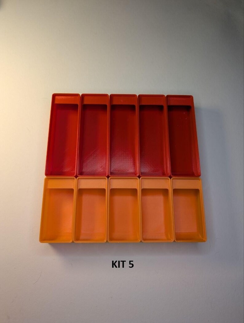 May include: A collection of rectangular plastic containers in shades of red and orange. The containers are arranged in two rows, with the top row in a darker red and the bottom row in a lighter orange. The text "KIT 5" is visible.