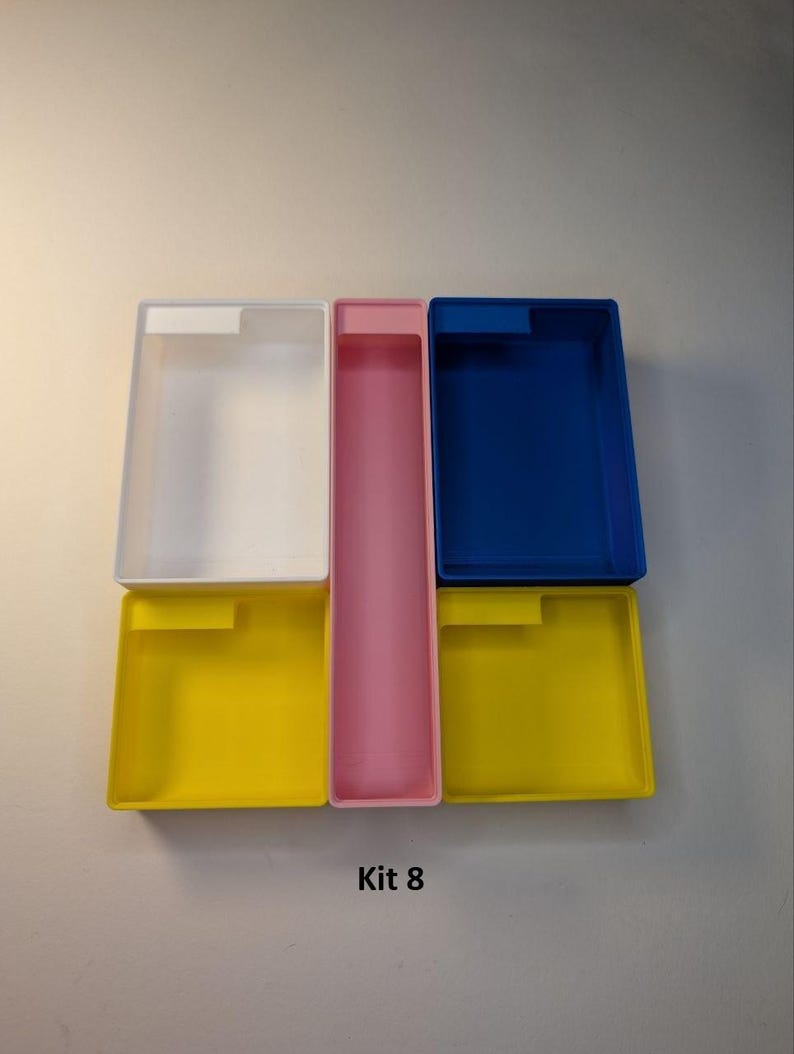 May include: A collection of colorful rectangular storage containers. The containers are in various colors, including white, pink, blue, and yellow. The text "Kit 8" is printed at the bottom of the image.