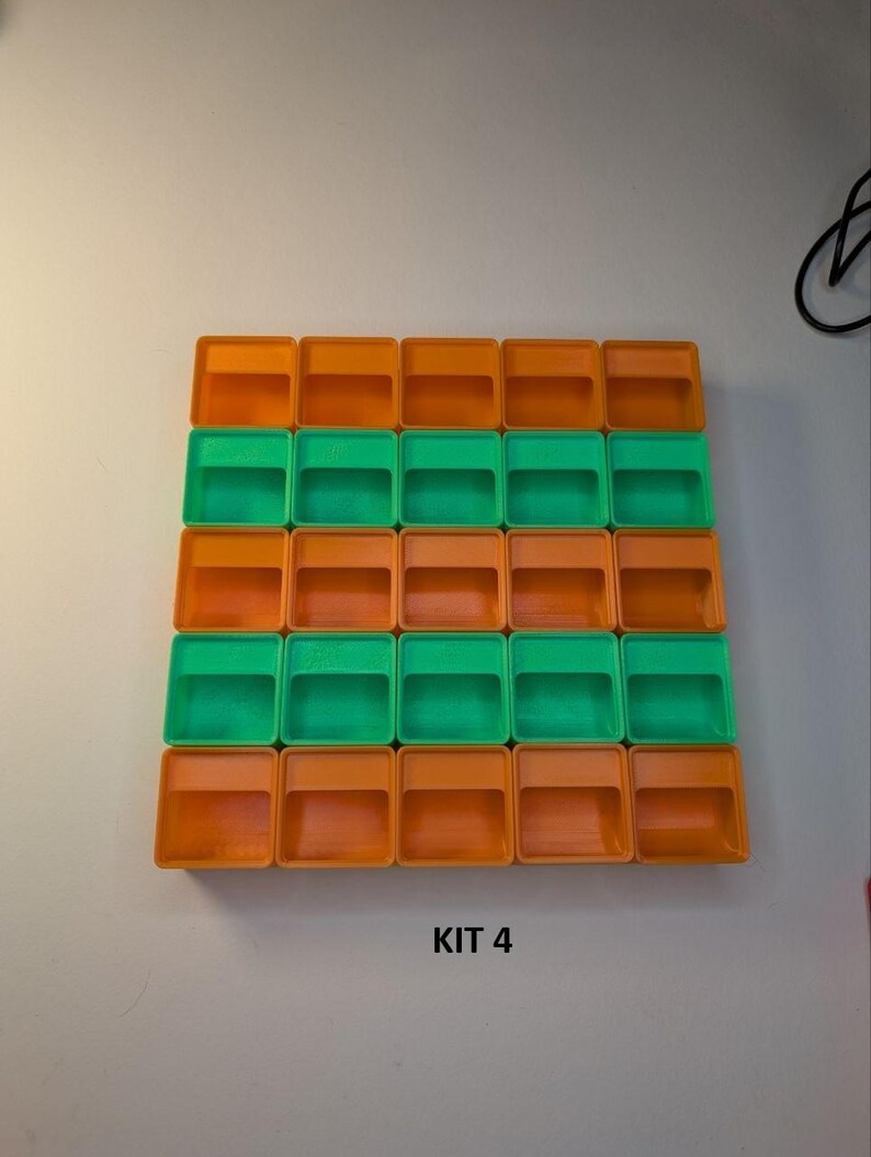 May include: A grid of twenty-four small, rectangular containers. The containers alternate between orange and green. The text "KIT 4" is printed in black at the bottom of the image. The containers are arranged in a square pattern.