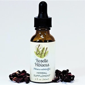 May include: A brown glass bottle with a black dropper top, labeled "Roselle Hibiscus Herbal Supplement 1 fl. oz (30ml)". Dried red hibiscus flowers are scattered around the bottle. The label has a green and white logo.