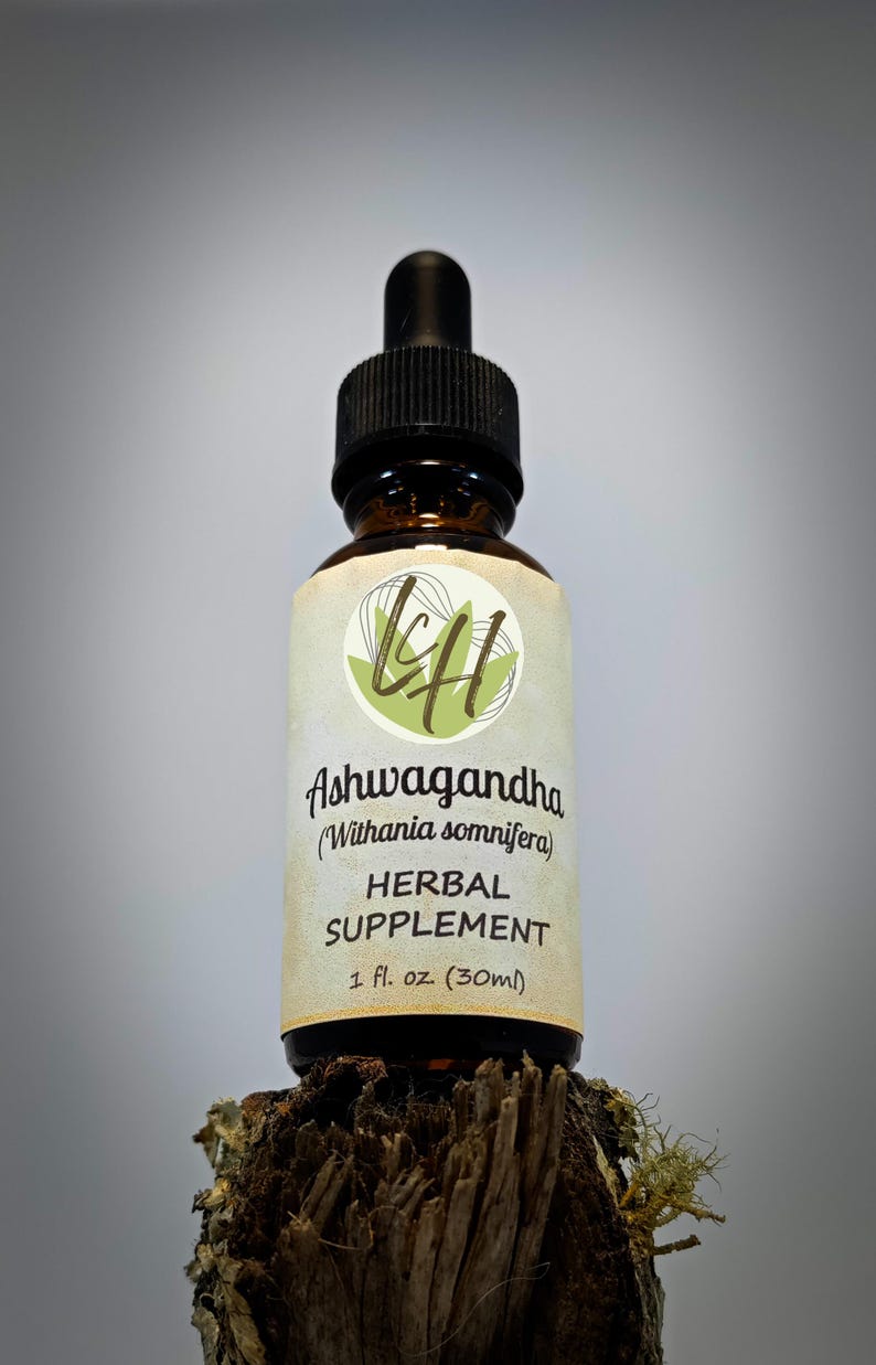 Op de afbeelding: Een bruine glazen fles met een zwarte druppeldop, met het label "Ashwagandha Herbal Supplement". Het etiket bevat de wetenschappelijke naam "Withania somnifera" en geeft de inhoud aan als 30 ml. De fles staat op een stuk hout.