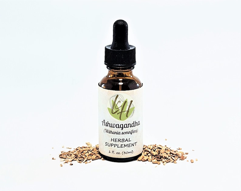 Op de afbeelding: Een bruine glazen fles Ashwagandha kruidensupplement met een zwarte druppelaar. Het etiket bevat de tekst "Ashwagandha (Withania somnifera) HERBAL SUPPLEMENT 1 fl. oz. (30ml)". De fles is omgeven door stukjes gedroogde wortel.