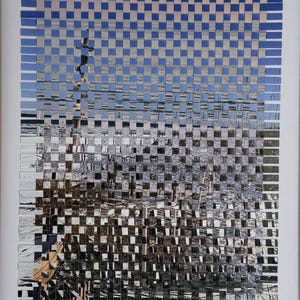 May include: A framed artwork featuring a woven design of a coastal scene. The artwork uses a grid pattern with alternating strips of blue sky and reflective water, creating a unique visual texture. The frame is made of light-colored wood.