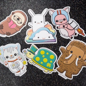 May include: A set of ten colorful stickers featuring various animals, including a turtle, a cat, a pig, a bunny, an otter, and a mammoth. Each sticker has a "Flat Bonnie" logo and a white outline.