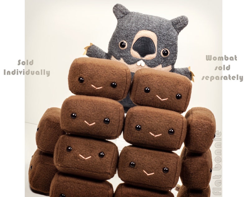 May include: A gray plush wombat toy is standing in front of a stack of brown plush blocks with smiling faces. The blocks are stacked in a pyramid shape. The text "Sold Individually" is on the left side of the image and the text "Wombat sold separately" is on the right side of the image.
