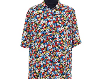 May include: A short-sleeved button-down shirt featuring a vibrant, dense floral pattern against a black background. The print consists of small, overlapping flowers in bright shades of red, blue, yellow, and white, covering the entire garment.