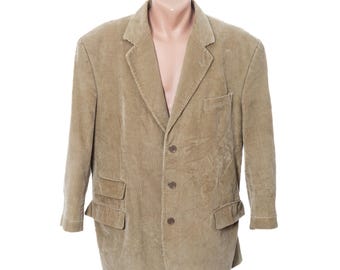 May include: A tan corduroy blazer with a notched lapel, three-button closure, and two front flap pockets. The jacket is displayed on a mannequin and has a classic, tailored design. The corduroy fabric has a vertical ribbed texture.