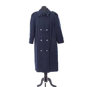 May include: A navy blue double-breasted trench coat displayed on a black mannequin. The coat has a classic design with a notched collar, shoulder epaulets, and multiple buttons. The coat is long, reaching the ankles.