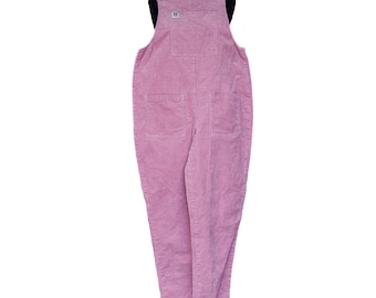 May include: A pair of light pink corduroy overalls featuring a bib pocket with a small white rectangular brand label, two large front patch pockets, and adjustable shoulder straps with metallic hardware fasteners, presented on a black mannequin.
