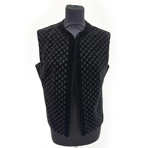 May include: A black velvet vest with a repeating cross pattern. The vest is sleeveless and has a high collar. The fabric appears soft and plush, with a subtle sheen. The vest is displayed on a black mannequin.