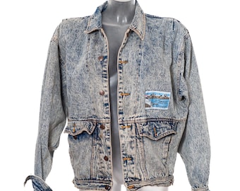May include: A light blue acid-wash denim jacket featuring a classic collar, long sleeves, and a button-front closure. The jacket includes two front flap pockets and a rectangular patch on the left chest with the text "TURPENTINE CANYON CLUB" and "LA MIRADA".