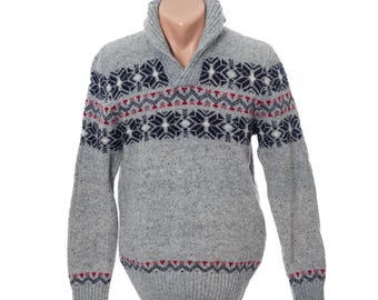 May include: A gray sweater with a shawl collar and a snowflake pattern in navy blue, red, and white. The sweater has long sleeves and a ribbed hem and cuffs. The snowflake pattern is repeated on the chest and sleeves.