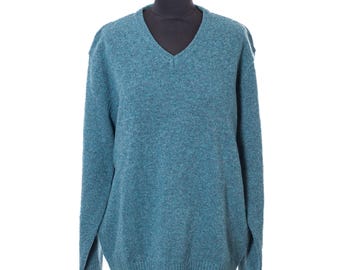 May include: A teal V-neck sweater displayed on a mannequin. The sweater has long sleeves and a ribbed hem and cuffs. The fabric has a textured appearance. The sweater is a solid color and appears to be made of a soft material.