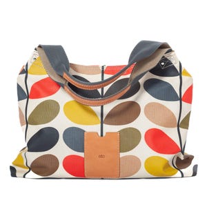 May include: A large tote bag with a colorful leaf pattern in red, yellow, brown, and gray on a cream background. The bag has a gray strap and brown leather handles. A small brown leather tag with the word "etc" is attached to the front.