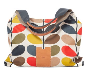 May include: A large tote bag with a colorful leaf pattern in red, yellow, brown, and gray on a cream background. The bag has a gray strap and brown leather handles. A small brown leather tag with the word "etc" is attached to the front.