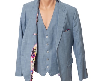 May include: A light blue three-piece suit displayed on a mannequin. The suit includes a blazer, vest, and trousers. The blazer has a plaid pattern and a pocket square. The vest has buttons. The interior lining of the blazer features a colorful graphic print.