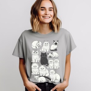 May include: A gray t-shirt featuring a collection of illustrated cats in various poses. The cats are depicted in black and white, with one solid black cat. The shirt is a casual style, suitable for cat lovers.