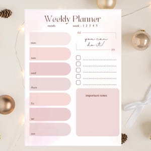 Peut inclure: Un planificateur hebdomadaire rose et blanc. Il comprend des sections pour chaque jour, une liste de tâches et un espace pour les notes. Le texte "Weekly Planner" et "you can do it!" sont visibles. Parfait pour l'organisation.