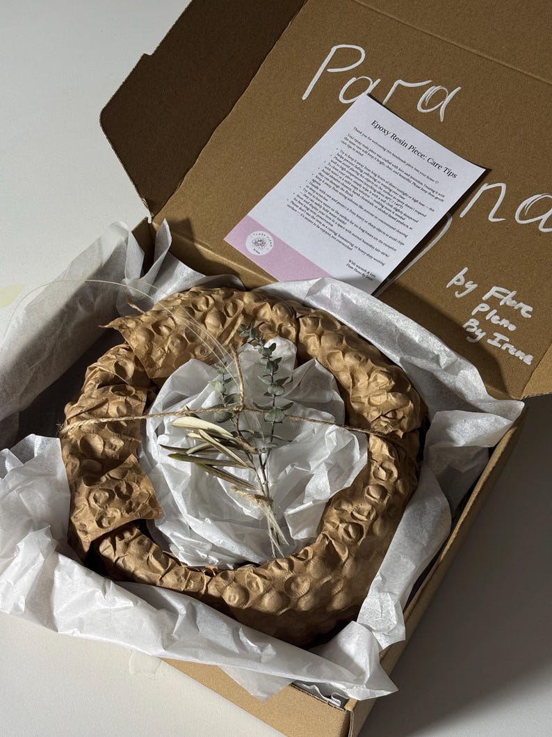 May include: A brown cardboard shipping box containing a circular object wrapped in brown honeycomb paper and white tissue paper. A small sprig of dried eucalyptus is tied to the top with twine. A care instruction card is included inside the box.