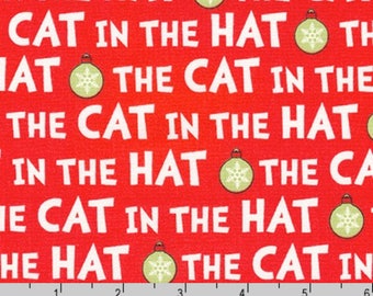 Puede incluir: Tela roja con un patrón repetido de la frase "El Gato en el Sombrero" y un adorno verde con un diseño de copo de nieve.