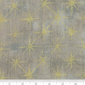 May include: A beige fabric with a repeating pattern of gold stars. The fabric has a subtle textured look.