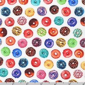 May include: A fabric pattern featuring a repeating design of colorful donuts. The donuts have various toppings and colors, including red, blue, green, brown, and yellow, set against a white background. The donuts are arranged in a grid-like pattern.
