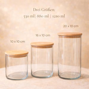 Pode incluir: Tr&ecirc;s frascos de vidro transparente com tampas de madeira de tamanhos diferentes. As dimens&otilde;es s&atilde;o: 10 x 10 cm, 16 x 10 cm e 20 x 10 cm. O texto "Drei Gr&ouml;&szlig;en: 530 ml | 880 ml | 1210 ml" tamb&eacute;m &eacute; vis&iacute;vel.
