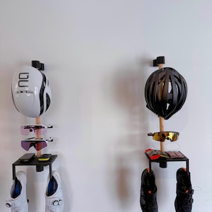 Peut inclure: Deux organisateurs muraux pour équipements de vélo. L'un présente un casque blanc, des lunettes de soleil roses et des chaussures de cyclisme blanches. L'autre a un casque noir, des lunettes de soleil dorées et des chaussures de cyclisme noires.