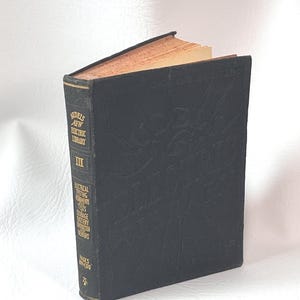 May include: A vintage black book titled "Audel's New Electric Library III." The book has gold-colored page edges and embossed lettering on the cover. The spine lists topics like electrical testing, components, and battery repairs. Pages 894-1370.
