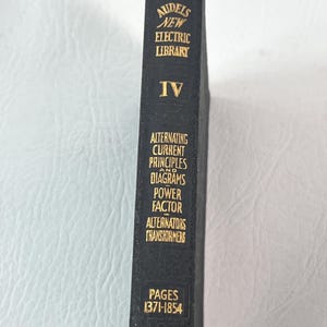 Puede incluir: Un libro negro con letras doradas, titulado "Audels New Electric Library, Volumen IV." El lomo detalla "Alternating Current Principles", "Diagrams" y "Transformers". Las p&aacute;ginas est&aacute;n numeradas de 1371 a 1854.