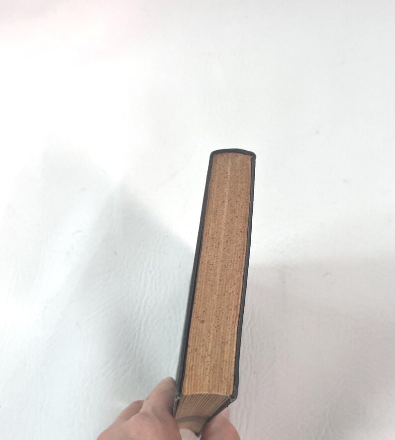 Puede incluir: Un libro antiguo con una cubierta de cuero marr&oacute;n oscuro y p&aacute;ginas envejecidas de color beige. El lomo del libro es visible, mostrando el desgaste del tiempo. Las p&aacute;ginas est&aacute;n ligeramente amarillentas, lo que indica la edad.