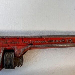 May include: A vintage red adjustable pipe wrench with the text "THE RIDGE TOOL CO ELYRIA OHIO U.S.A." and the number "14". The wrench has a textured handle and adjustable jaws.