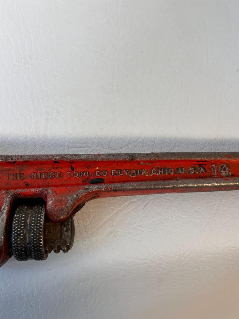 May include: A vintage red adjustable pipe wrench with the text "THE RIDGE TOOL CO ELYRIA OHIO U.S.A." and the number "14". The wrench has a textured handle and adjustable jaws.