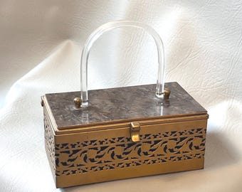 Bolso de mano tipo caja de filigrana en tono dorado de los años 50, con asa de lucita nacarada.