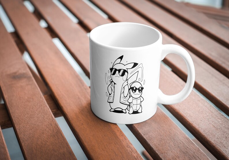 May include: White ceramic mug featuring a black and white illustration of Pikachu and Squirtle wearing sunglasses. The mug has a curved handle and is set against a wooden background. A fun, pop culture themed item.