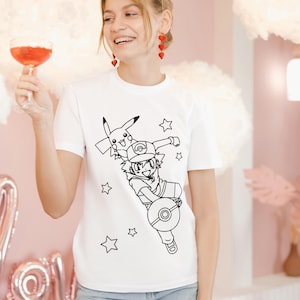 May include: White t-shirt featuring a black line drawing of a cartoon character with a Pikachu and stars. The person is wearing blue jeans and red earrings. The background is pink with cloud-shaped decorations.