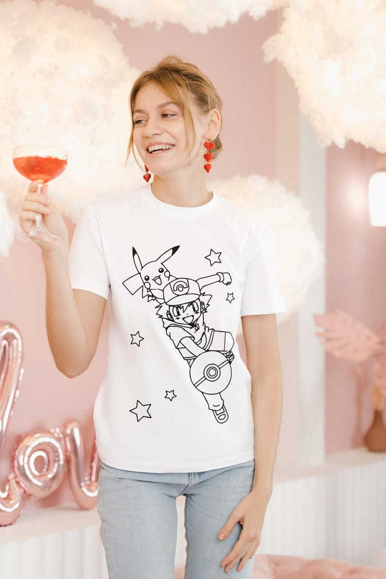 May include: White t-shirt featuring a black line drawing of a cartoon character with a Pikachu and stars. The person is wearing blue jeans and red earrings. The background is pink with cloud-shaped decorations.