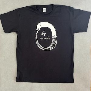 Op de afbeelding: Een zwart t-shirt met korte mouwen voorzien van een witte grafische print van een ouroboros, een slang die zijn eigen staart opeet, met de Griekse tekst "ἓν τὸ πᾶν" in het midden van de cirkelvorm die door het lichaam wordt gevormd.