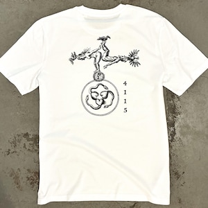 Pode incluir: Uma t-shirt branca de manga curta com uma impressão gráfica preta no peito. O design mostra duas figuras numa pose equilibrada sobre um emblema circular contendo três serpentes e corações entrelaçados, com o texto vertical 4 1 1 5.