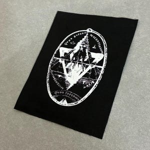 May include: A rectangular black fabric patch featuring a white screen-printed graphic of a bearded figure within an oval border. The design includes a triangle, celestial symbols, and the Latin text Quod Superius, Quod Inferius, and Microcosmos.